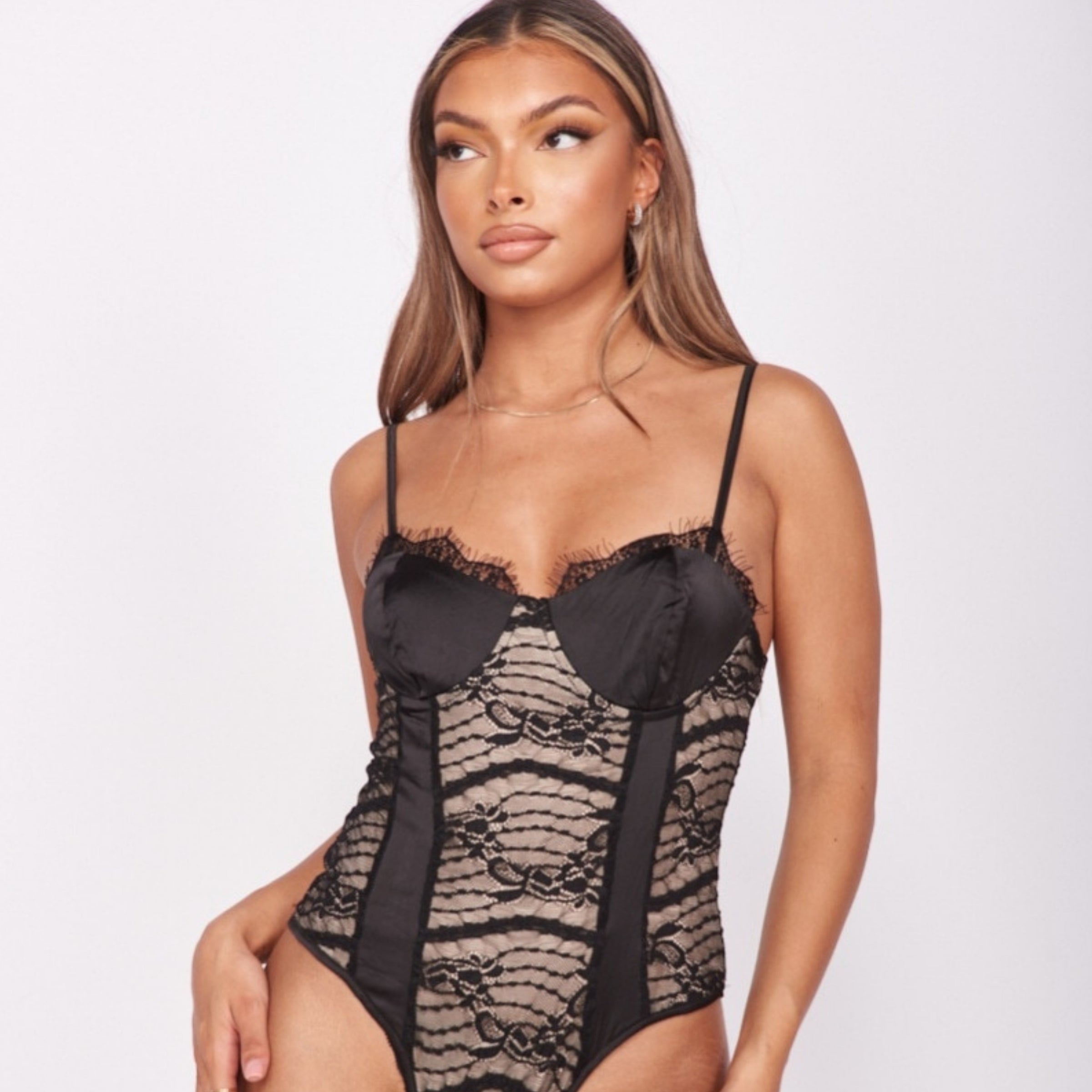 4ever Stunning Bodysuits and Tops Collection Tile. Model wears a black and cream satin and lace bodysuit.