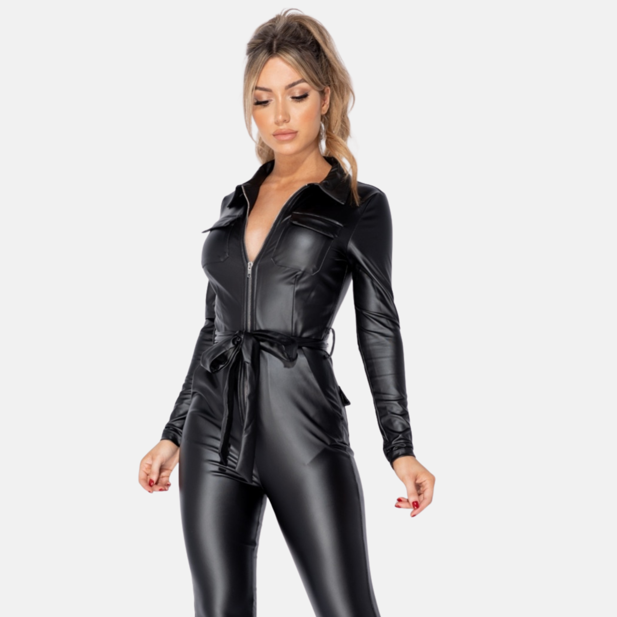 Female model wears a faux leather jumpsuit with front zip fastening.