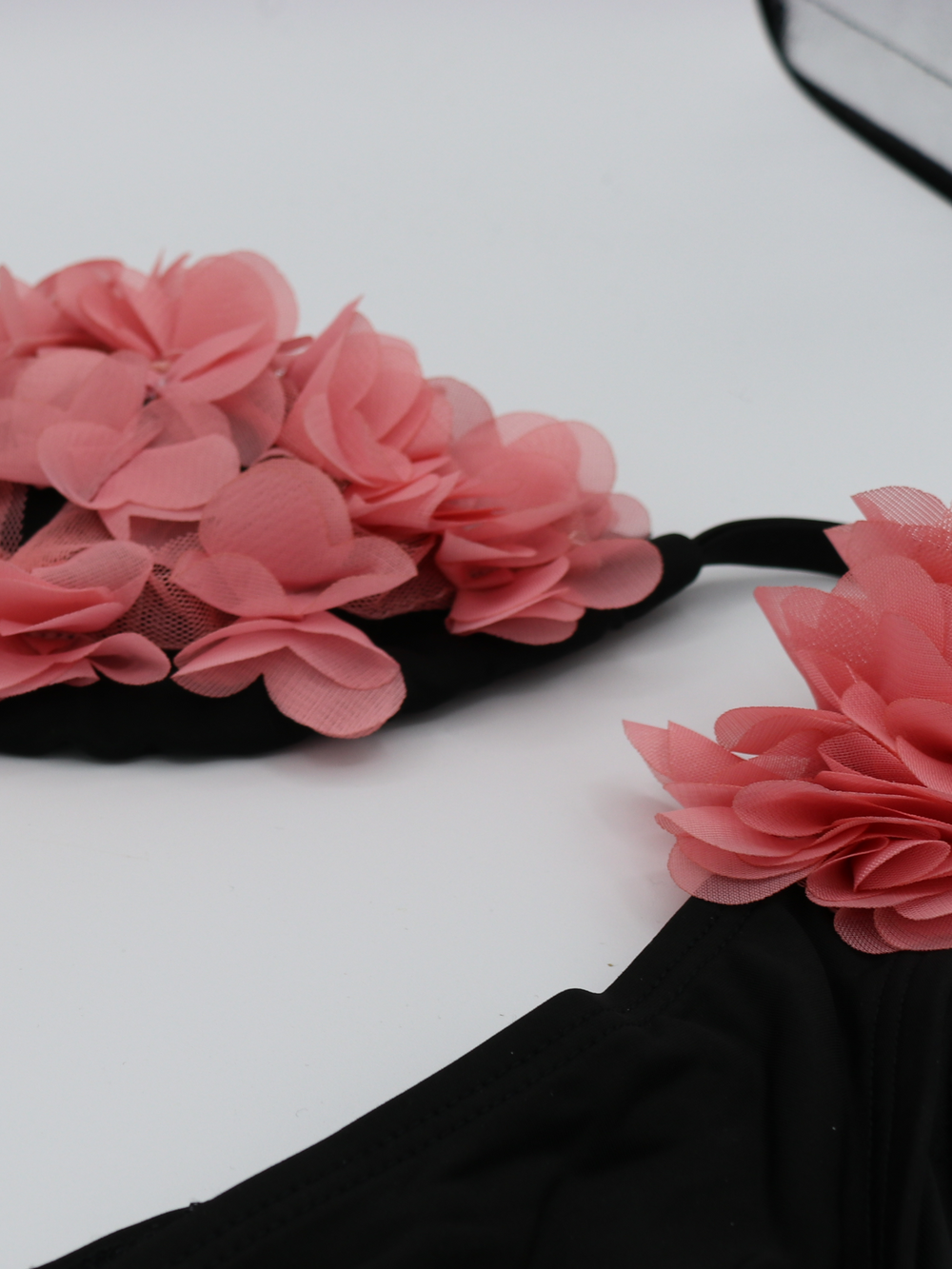 Close up of black bikini triangle top and matching brief. This statement bikini has 3d chiffon petal detailing on the bra and at the sides of the brief. A statement, glamorous bikini.