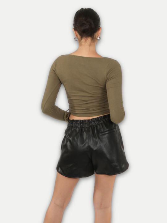 Model wears  pu leather running shorts, with front side pockets and a back pocket at the rear. The thick pu material demonstrates the high quality of the leather look shorts. Model stands with her back to the camera, the back pocket can be seen.