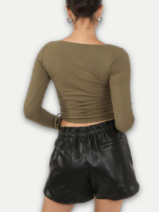 Model wears  pu leather running shorts, with front side pockets and a back pocket at the rear. The thick pu material demonstrates the high quality of the leather look shorts.  Model stands with her  back to the camera. The back of the faux leather shorts can be seen.
