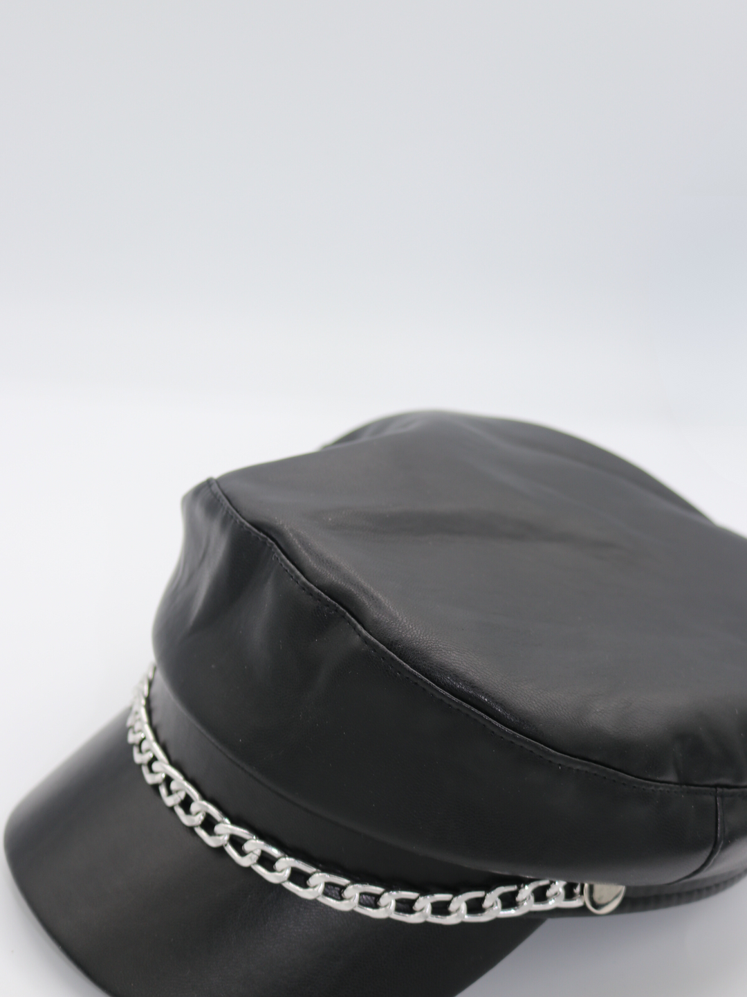 Side profile of the pu leather baker boy hat, demonstrating the front of the cap and the front silver detailing.