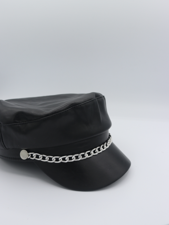 Side view of the baker boy PU hat with silver chain link at the front. The side profile and some of the front of the cap can be seen.