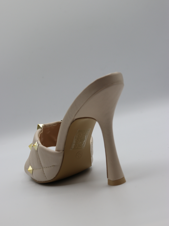 Cream quilted faux leather mule heels with gold studded heels. The back of the heel is visible, showing tghe cream slim heel.