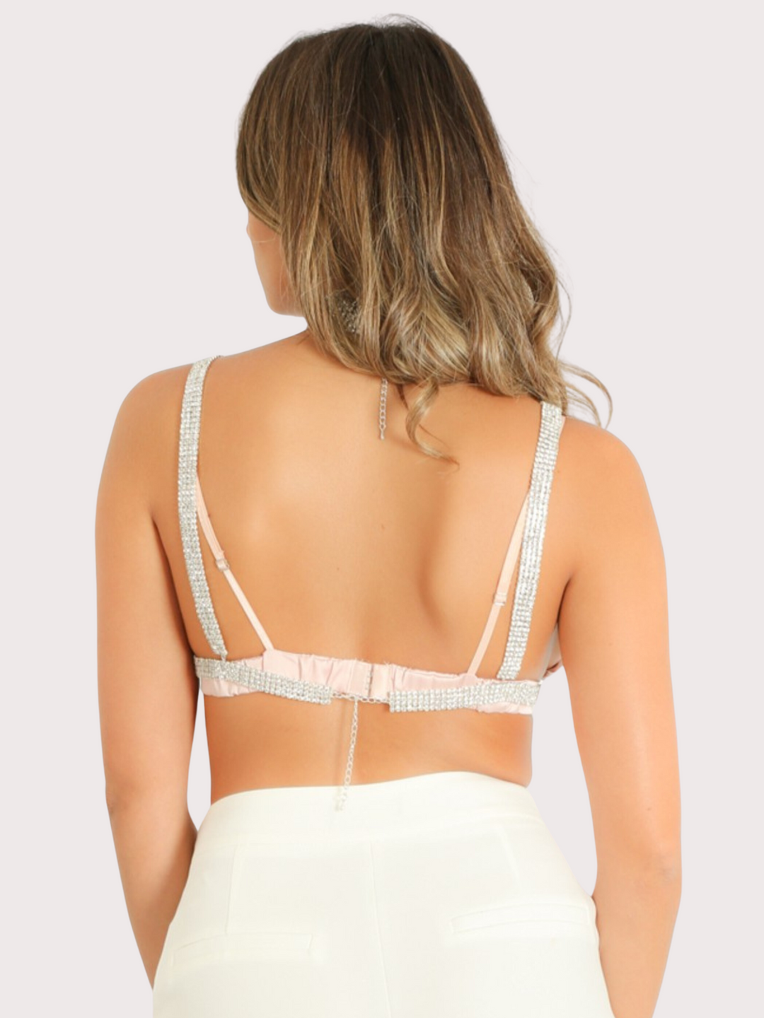 Model has her back to the camera. The adjustable strap can be seen. Model wears diamante triangle cut out with adjustable diamante choker and adjustable chain back fastening.