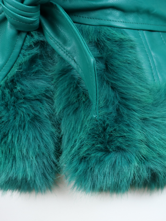 Close up of the bottom of the green faux fur trim and green faux leather removable belt.