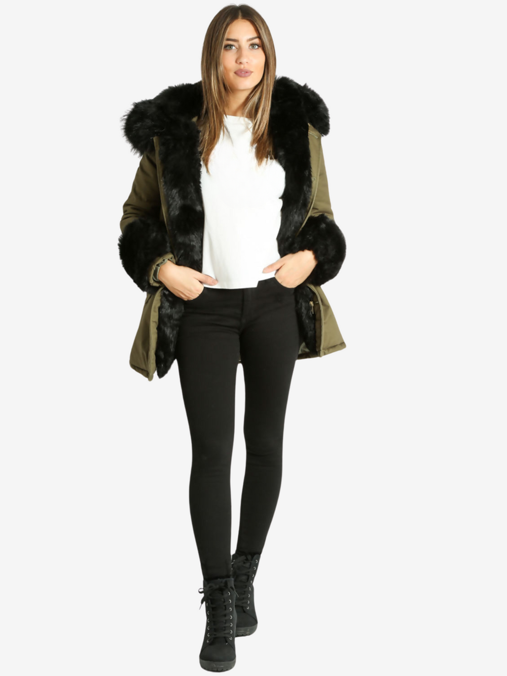 Full length shot. Model wears a green khaki jacket with black faux fur cuffs, a hood with faux fur trim and detachable faux fur frontal flaps. Model stands with one leg slightly in front of the other.  Model wears black jeans and a white top.