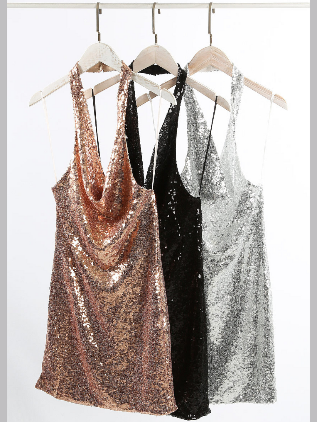 Photo of the sequin clothing rack, showing a cowl neck halter neck and a mini dress design. The rose gold, black and silver sequin dresses can be seen on the rack.