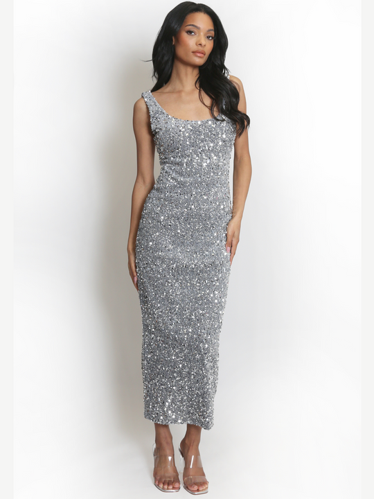 Full length shot. ength shot. Model weas a  deluxe silver sequin midi dress, with a square neckline and a sleeveless cut. The model has brown skin and long black hair. The model faces the camera, the front of the sequin dress can be seen, she places her hands by her sides and looks into the camera.