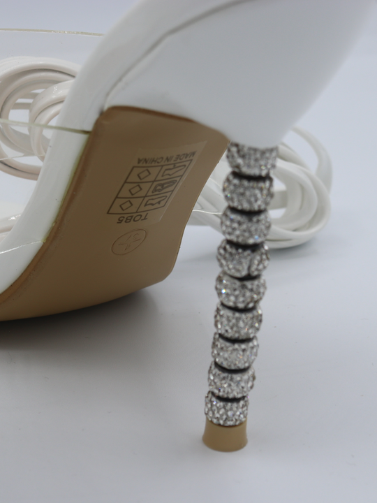 White strappy mules shoes with diamante stiletto heel.  Closeup of the diamante heel is visible. Shoe is turned at a slight angle.