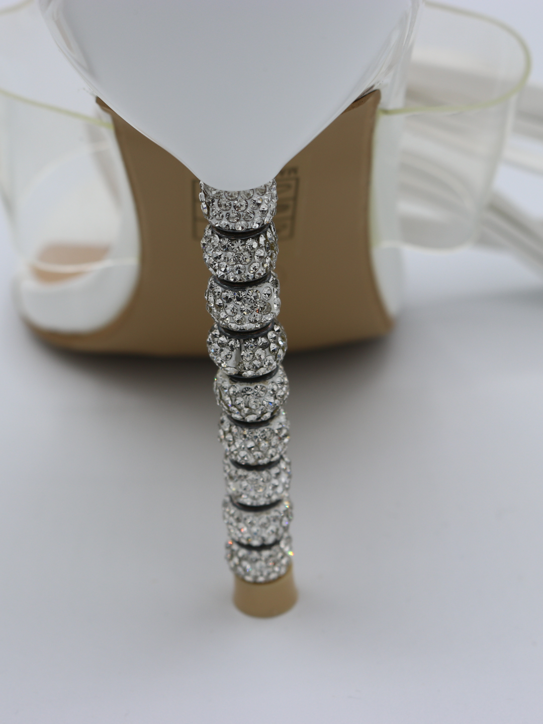 White strappy mules shoes with diamante stiletto heel. This is a statement shoe with a diamante heel.  A closeup of the diamante heel is visbible.
