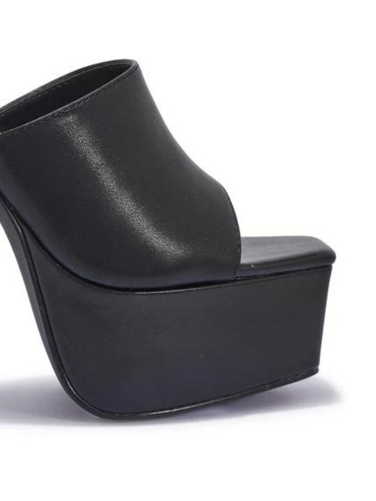 Black heeled mules that have a thick platform base and stiletto shoes. The picture shows the thick platform and the shoes band.