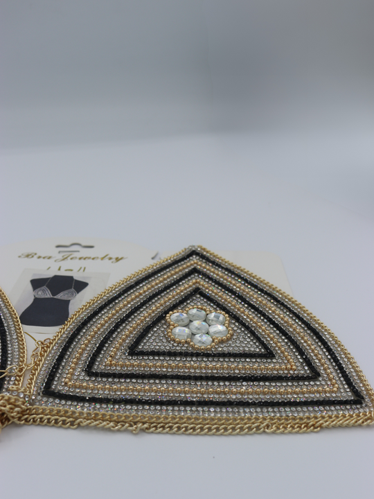 Close up of centre of the jeweled diamante bralette. The close up demonstrates the diamante and rhinestone design.  The gold chain fastening can be seen.  The packaging picture can be seen in the background.