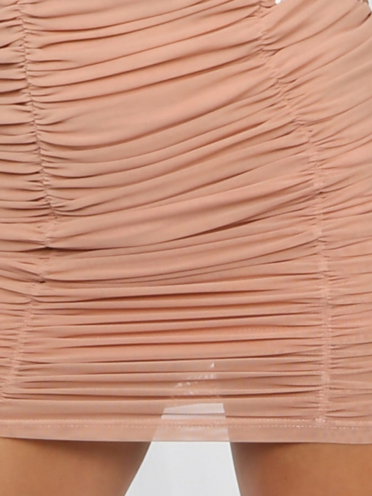 Extreme close up of skirt. Model wears a peach coloured ruched mini skirt tha has an elasticated waist.