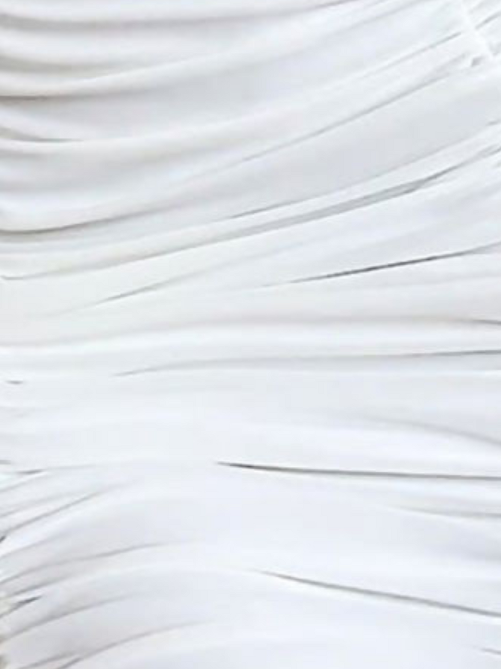 Closeup of the slinky ruched material. The dress has double lined slinky white ruched midid dress with draping detailing at the torso