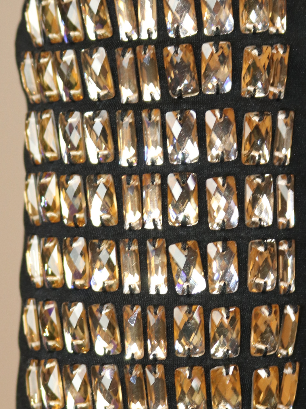 4ever Stunning Deluxe Premium black midi dress with gold rhinestone jeweled arms and chunky gold back zip fastening. Photograph shows a closeup of the rhinestone jeweled sleeves.