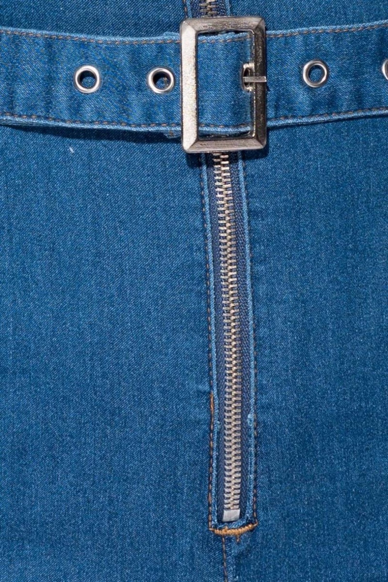 Closeup of the denim material. The silver zip and denim belt is visible.