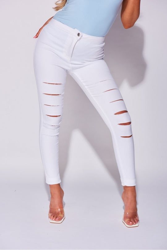 Model wears white jeggings with slash front detailing.  Model stands with one leg to the side.