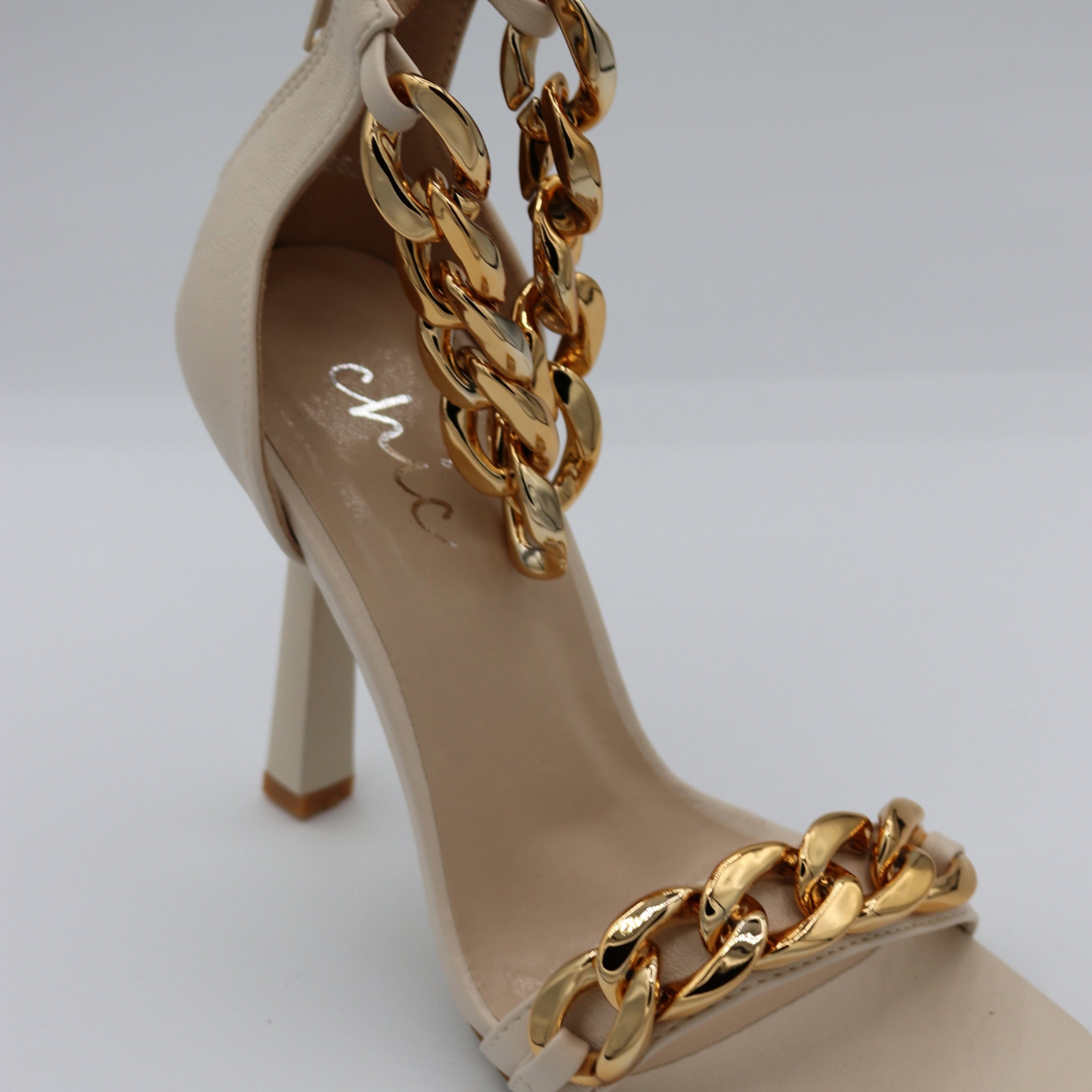 4ever Stunning Shoe Collection Tile. Close Up of a beige heeled shoe with a gold chain ankle strap.