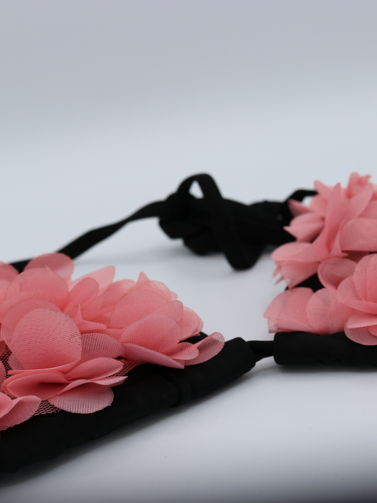 Close up of black bikini triangle top with chiffon 3d petals on the bra and brief. This statement bikini set has an unusual pink 3d petal design and tie fastening bikini top strap. 