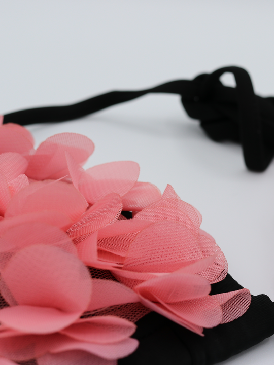 Extreme close up of black bikini triangle top with chiffon 3d petals on the bra and brief. This statement bikini set has an unusual pink 3d petal design and tie fastening bikini top strap.