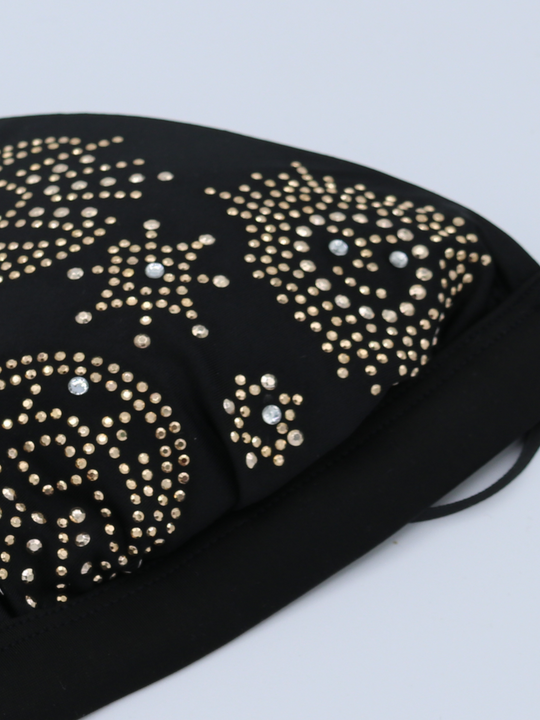 Closeup of black triangle bikini top with gold embelsihed studs and diamante detailing. The pattern on the bikini has cosmic designs. A statement and glamorous bikini with harness strap.
