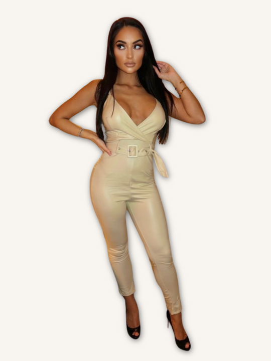 Model wears a beige faux leather jumpsuit with belted waist and plunging neckline. Model looks to the side, placing one hand on her hip and the other in her hair. The whole of the front of the jumpsuit can be shot. 