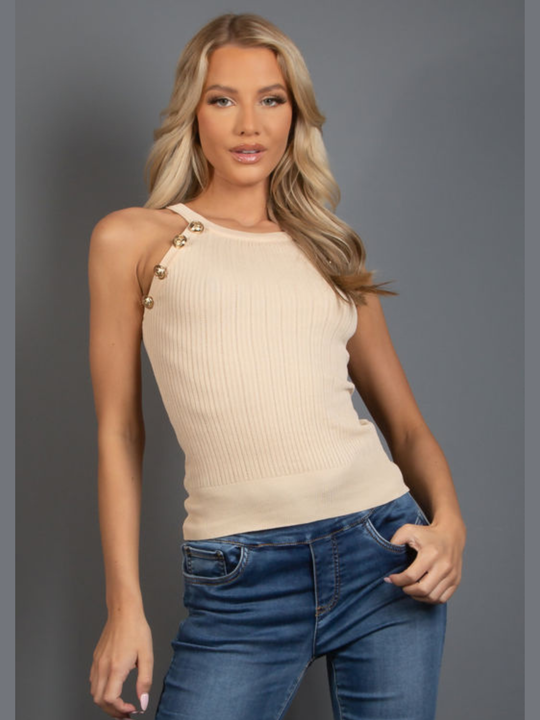Model stands in front of a plain background, who wears a beige ribbed tank top, with front gold button detailing. The model has tanned skin and long blonde  hair, she faces the camera and places one hand on her hip and the other by her side.   