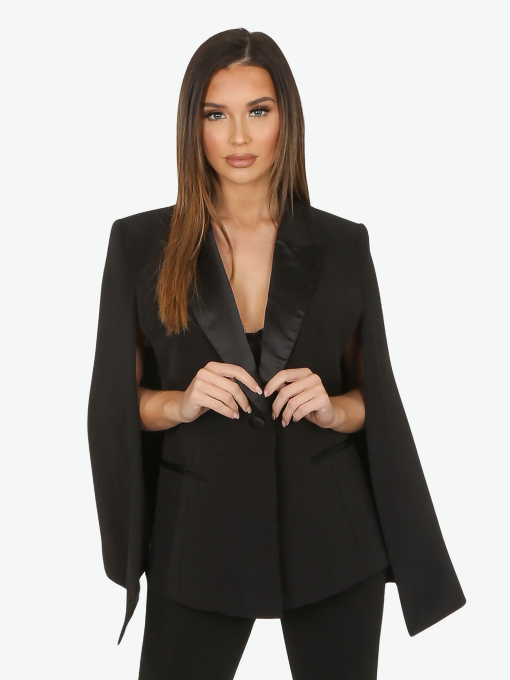 Model wears black cape blazer with side split and black satin lapel. The blazer has front button fastening.  Model places both her hands in front, touching the black satin lapel. 