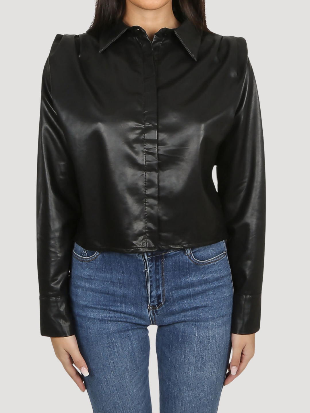 Model wears black faux leather shirt with pleated shoulders and long sleeve. The pu cropped front button shirt and collard neck. Closeup of the front of the shirt is visible, model stands with both hands at her sides.