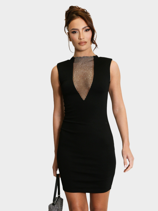 Model stands in front of a plain background, she wearsd a black sleeveless midi dress, with v neck diamante net design and bodycon fit. The model has tanned skin and brown hair that she has in a bun, she faces the camera, tilting her head slightly to the side, placing both hands by her side and holds a diamante bag. 