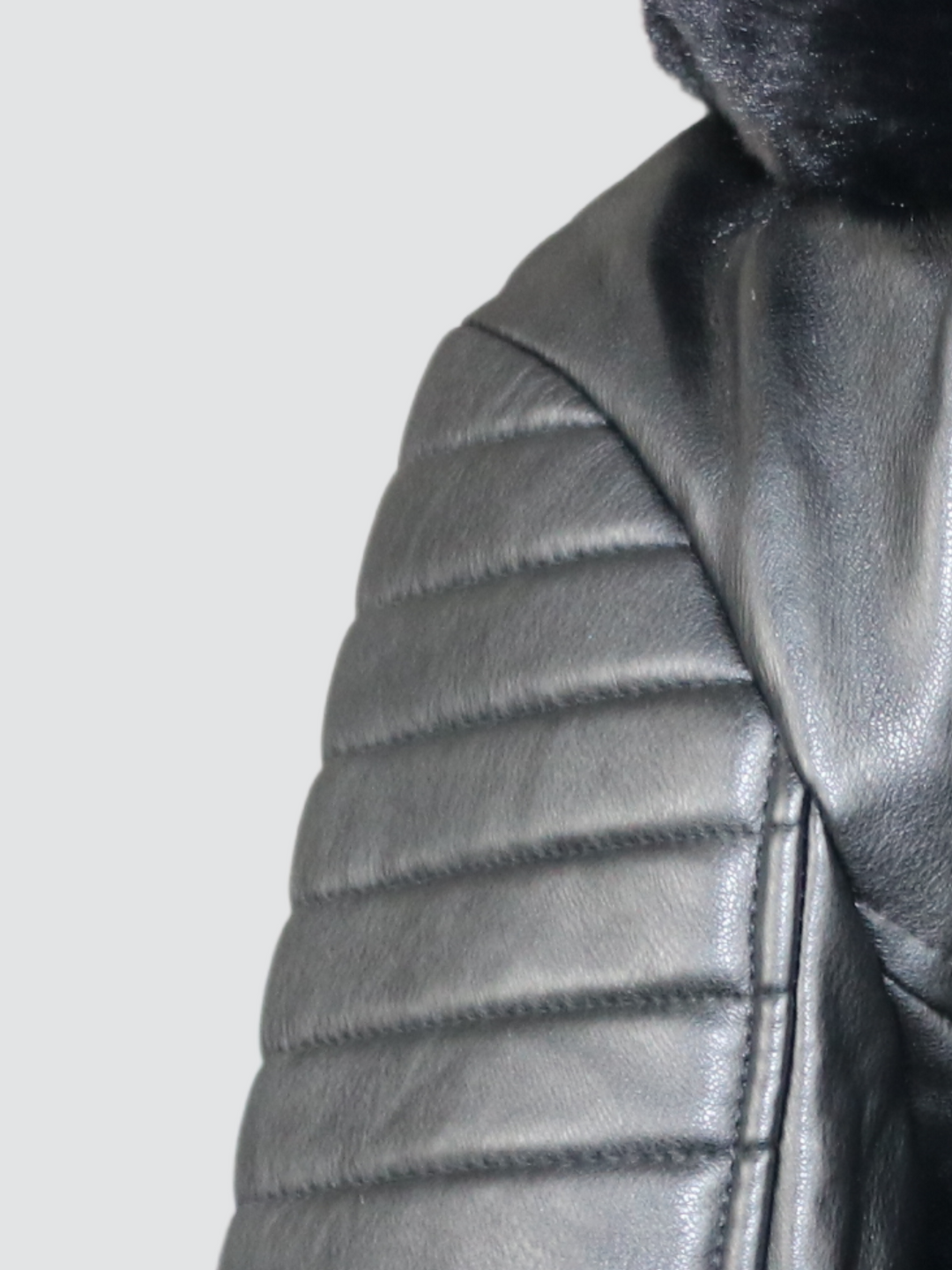 Close up of the shoulder panelled detailing of the faux leather biker jacket with faux fur trim.