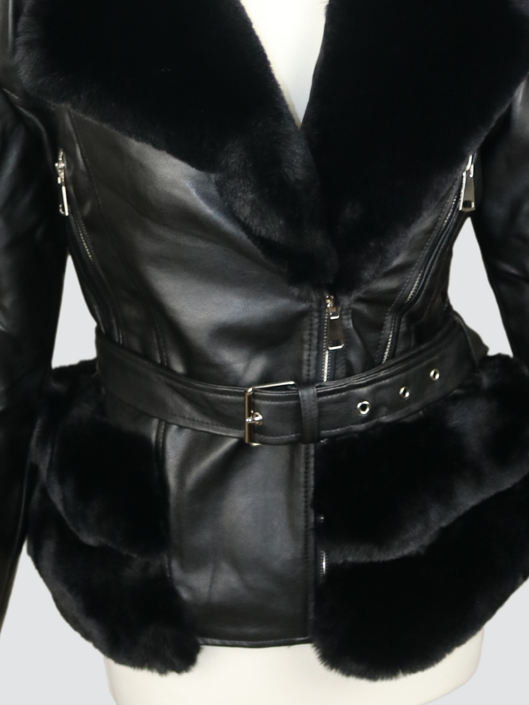 Ghost manequin wears a biker faux leather jacket with faux fur trim. The jacket has leather panelled detailing at the sleeves and exposed asymmetric chunky zip fastening. The faux leather jacket has a removable faux  belted waist.  A close up of the trunk of jacket can be seen, including a belted waist 