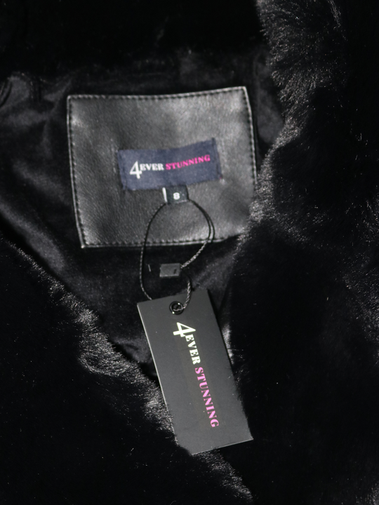Closeup of the interior of the faux leather jacket with faux fur trim. The interior faux fur lining can be seen as well as the 4ever Stunning logo. 
