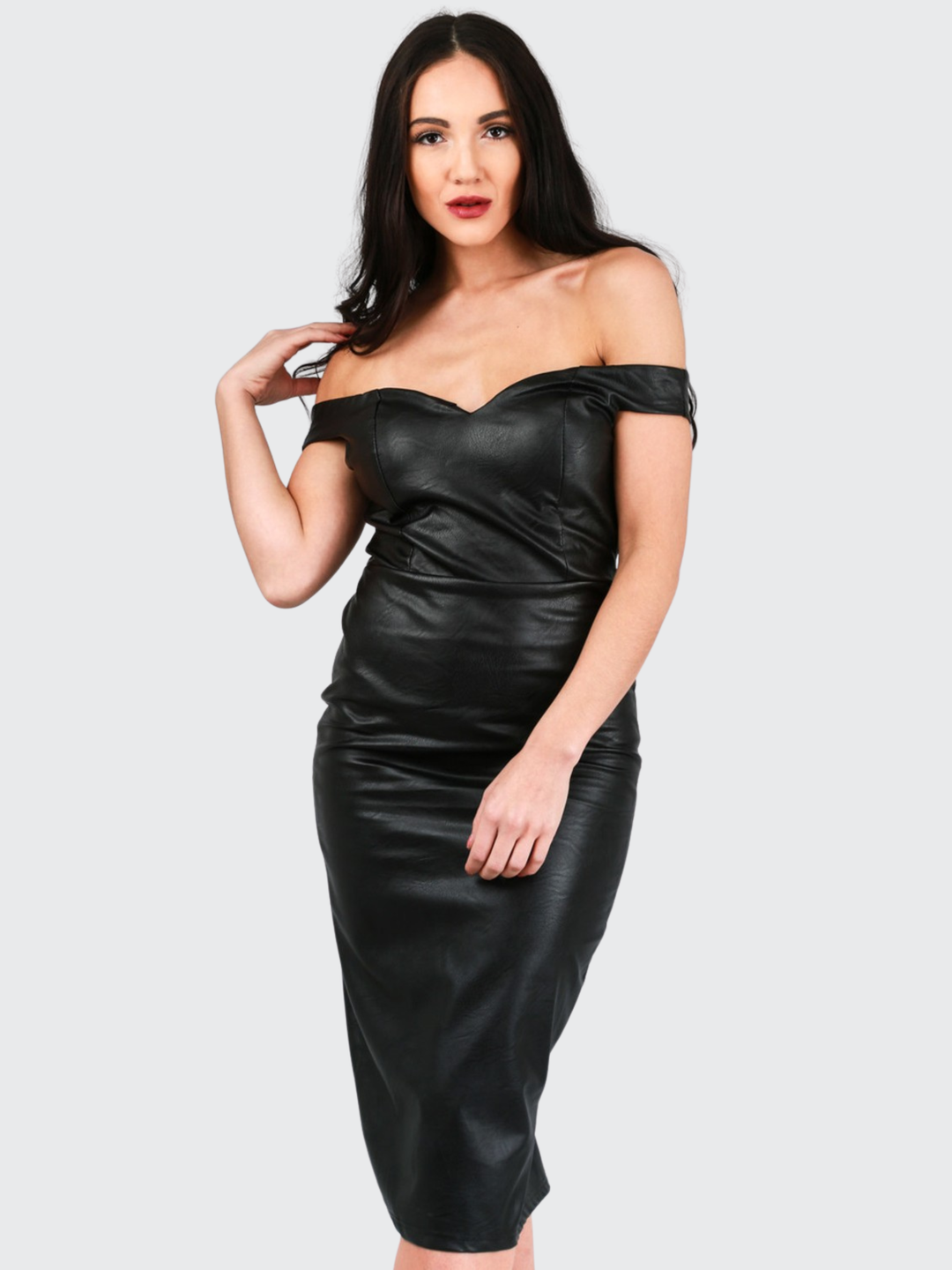 Female model stands in front of a plain background. The model faces the camera and wears a faux leather pu midi dress, with off the shoulder bardot design, sweetheart neckline and zip back design. The model has tanned skin and long black hair, she places one hand on her shoulder and the other on her thigh. 
