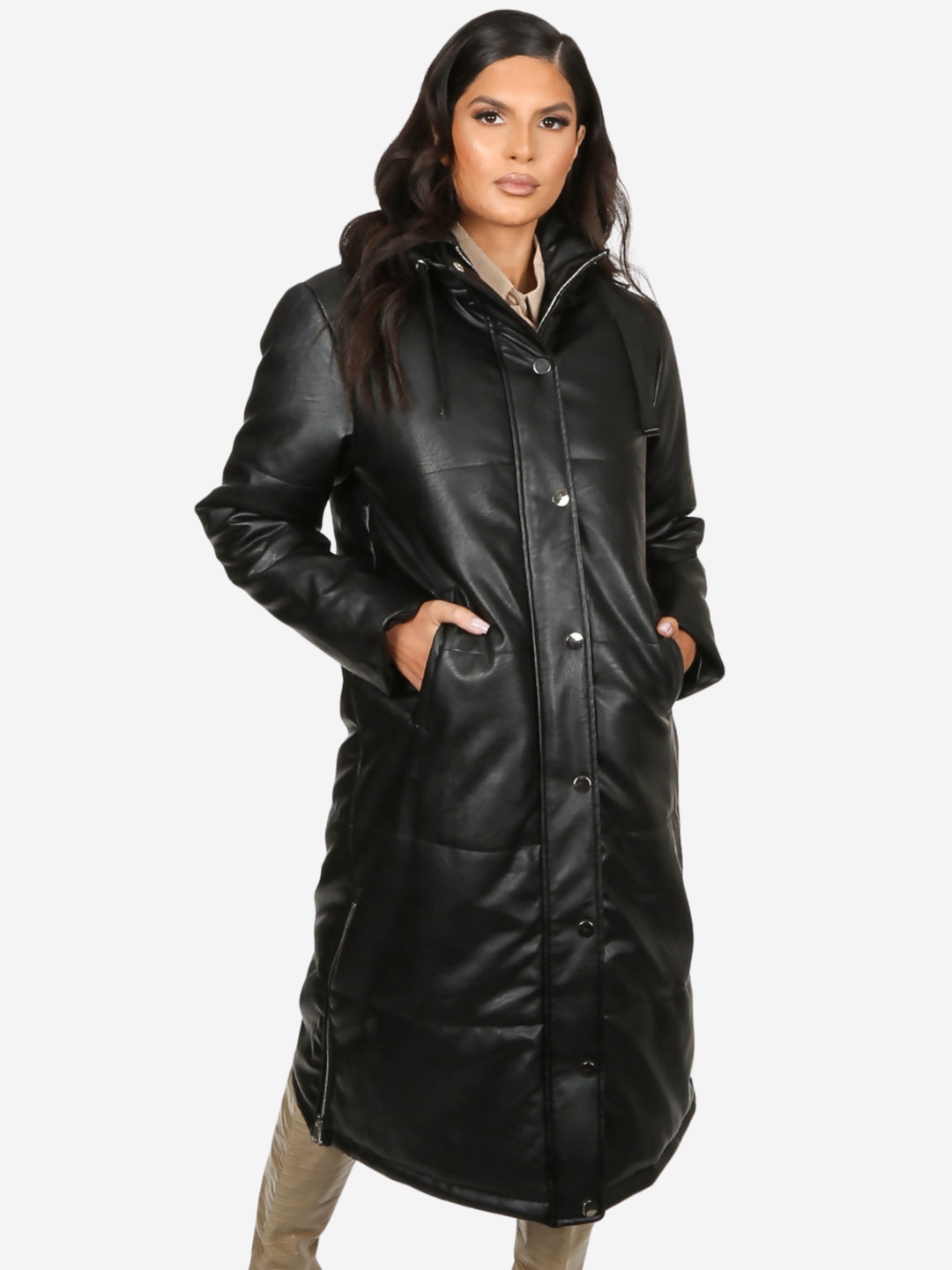 Model stands in front of a plain background, she wears a longline black faux leather quilted coat, with zip front and front button fastening.  The model has tanned skin and long dark brown hair, she faces the camera placing her hands in the coats side pockets.