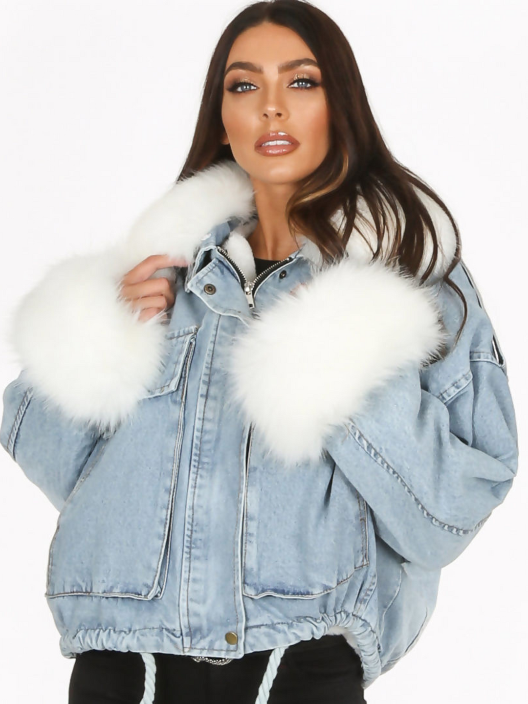 Model wears an oversized denim jacket with a white faux fur collar and white faux fur cuffs. Model wears the jacket closed and looks directly into the camera. 