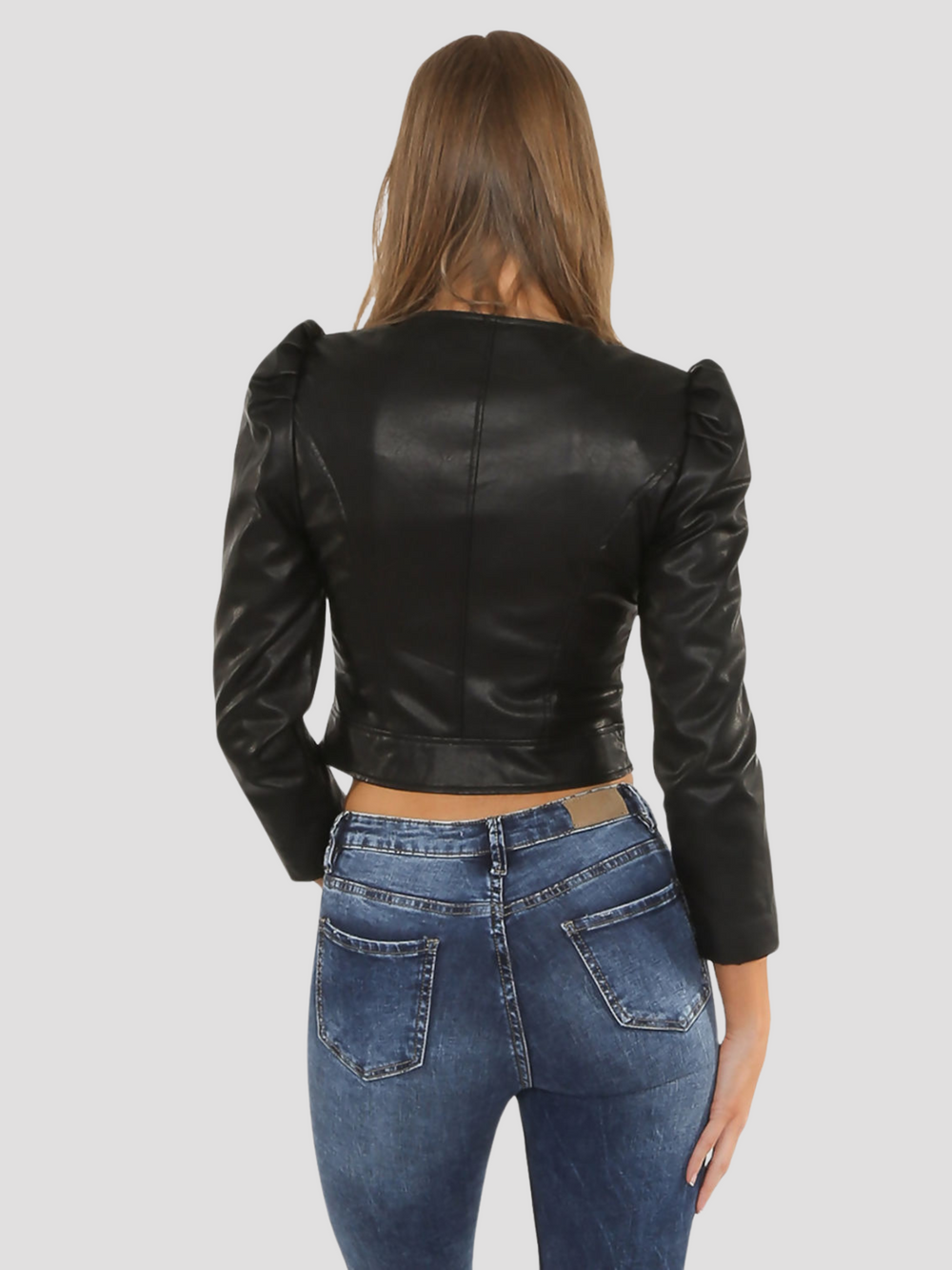 Model wears a leather look faux leather cropped jacket with puffed shoulders and long sleeves. Model stands and faces the camera with the jacket zipped up. Model stands with her back to the camera. The back of her jacket can be see, demonstrating the visible puffed sleeves and tailored fitted back of the jacket.