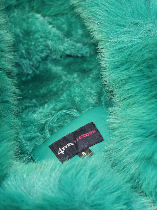 Close up of the interior of the green faux leather jacket with fur fur trim. The picture demonstrates that the interior of the jacket is fully lined with faux fur.  The 4ever Stunning label can be seen. 