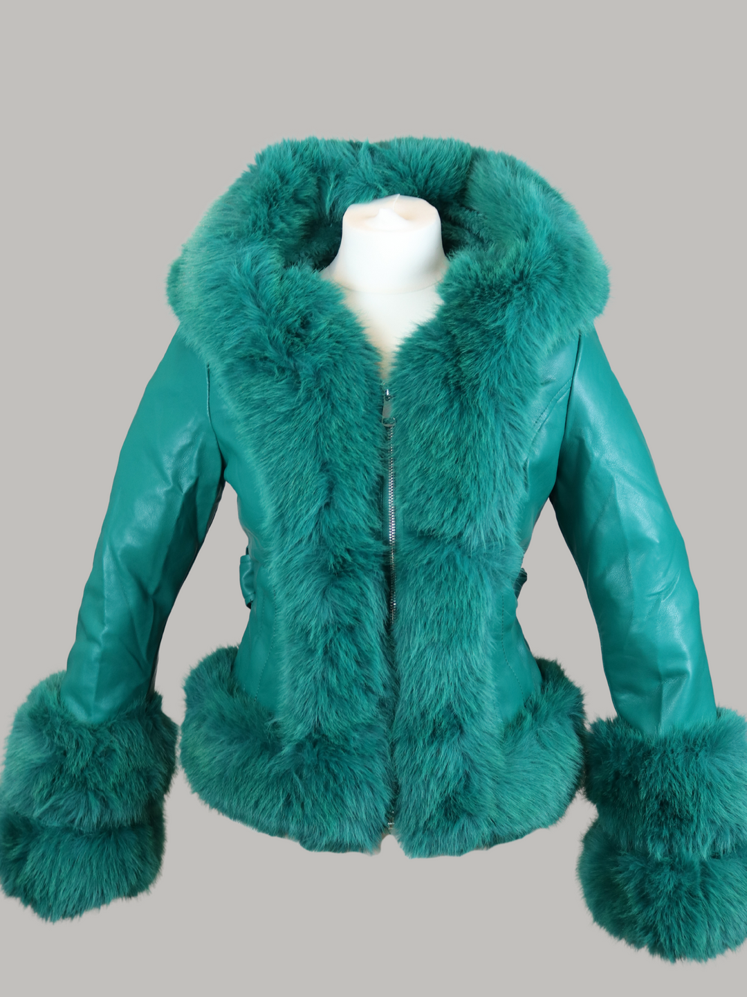 Ghost manequin wears a green faux leather jacket with green faux fur trim. The  green jacket has a faux fur hooded trim and large faux cuffs at tehh sleeves and a faux leather belt.  Ghost manequin wears the green faux leather jacket without the removable belt.