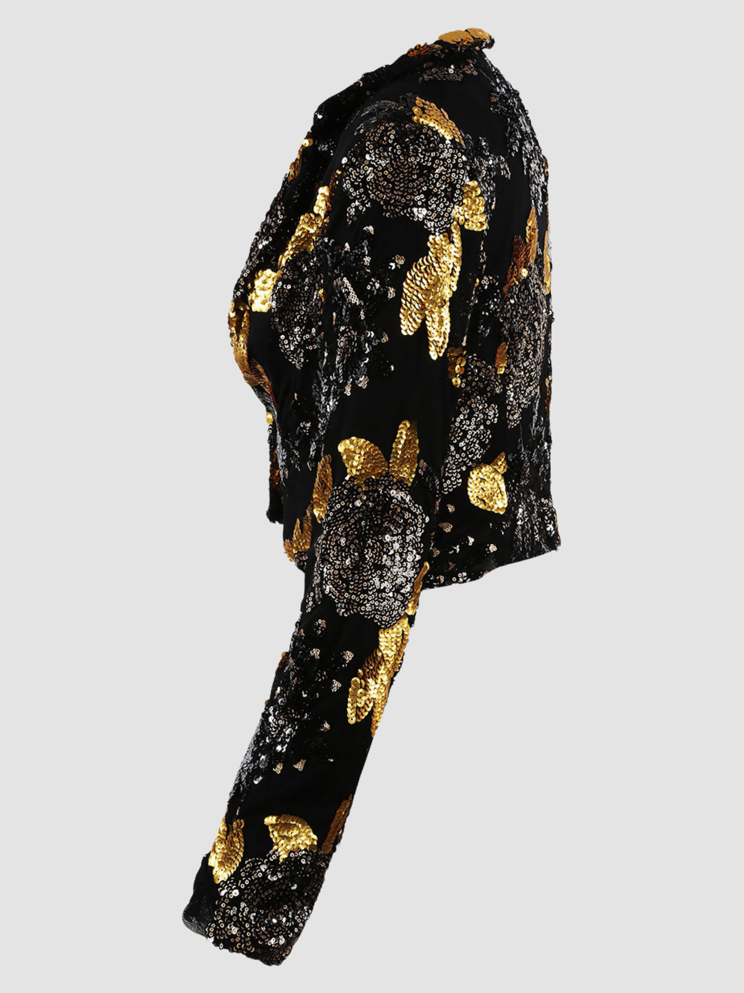 Ghost mannequin stands in front of a plain background. The ghost mennequin wears a black and gold sequinned cropped blazer with open front and long sleeves.The black and gold sequinned blazer has an open front and a luxe design. The ghost mannequin stands to the side, the side of the blazer can be seen, including the sequinned long sleeves. 