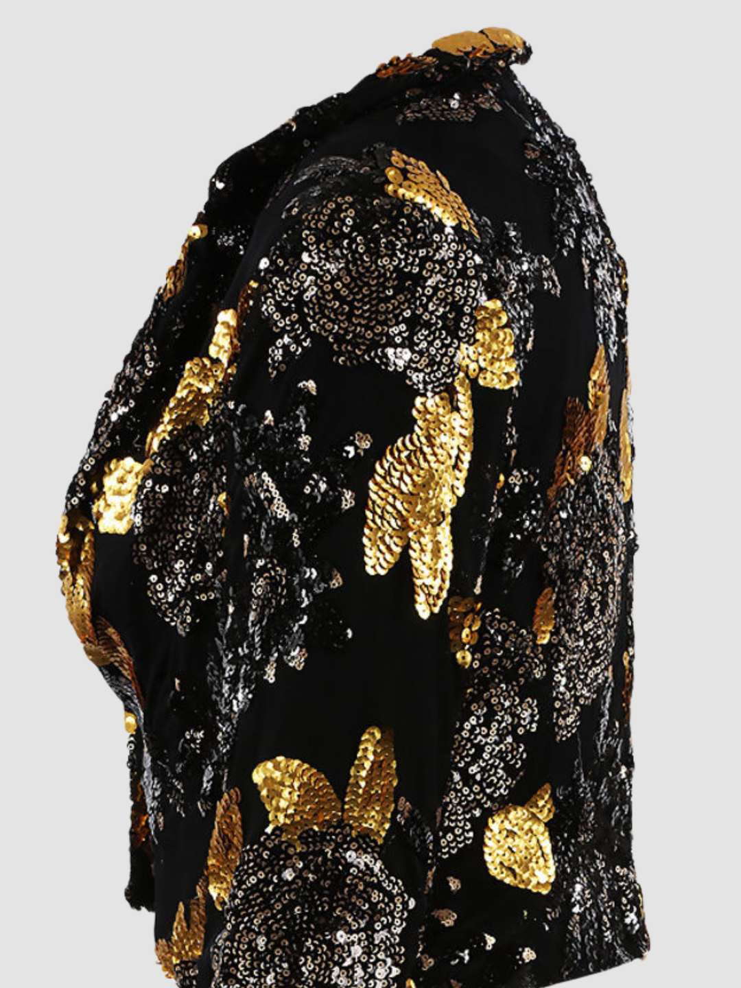Close up. Ghost mannequin stands in front of a plain background. The ghost mennequin wears a black and gold sequinned cropped blazer with open front and long sleeves.The black and gold sequinned blazer has an open front and a luxe design.  The ghost mannequin stands to the side, the side of the blazer can be seen, including detailed gold and blak sequinned design.