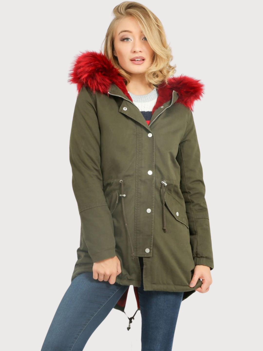 Model wears green khaki parka jacket with  burgandy faux fur hooded trim. The coat has a zip and front button fastening and adjustable string tightening. Model faces the camera, placing one foot slightly to the side. The sides of the burgandy faux fur can be seen. 