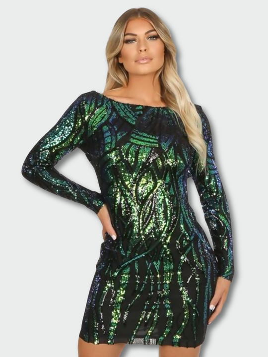 Model wears long sleeved green and black sequined midi dress with open back. Model faces the camera and stands with one hand on her hip and the other by her side. 