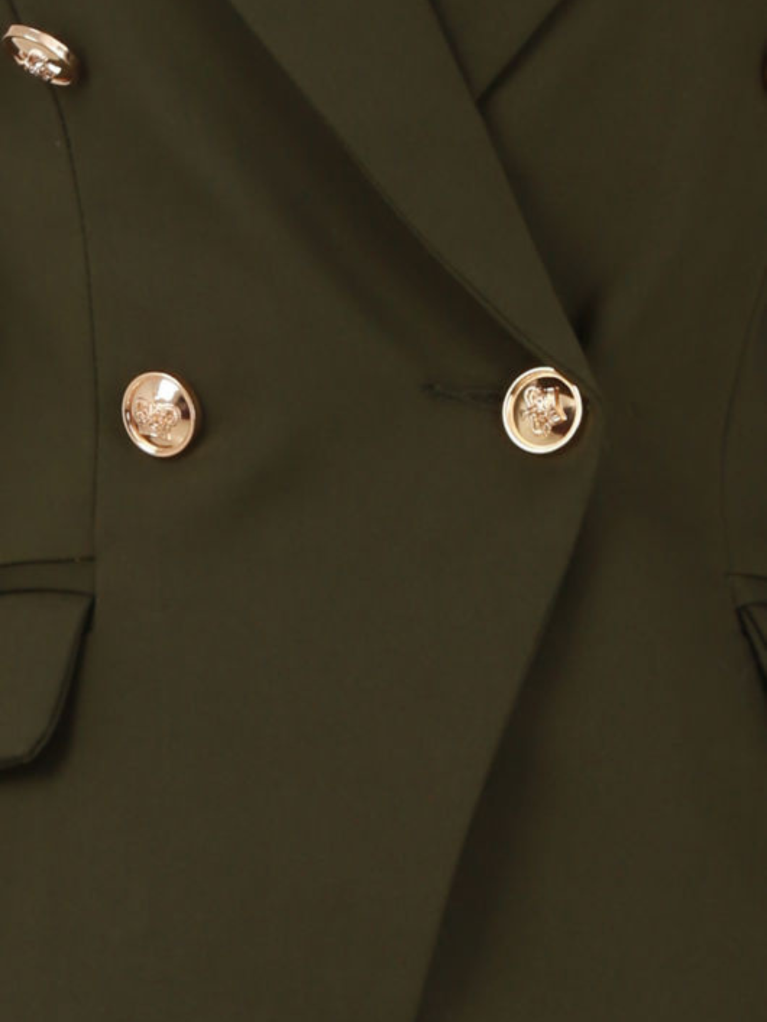 Close up. host mannequin stands in front of a plain background. A double breasted khaki  blazer with gold military button detailing and faux side pockets. 
