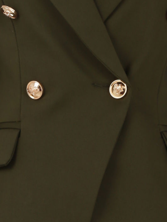 Close up. host mannequin stands in front of a plain background. A double breasted khaki  blazer with gold military button detailing and faux side pockets. 