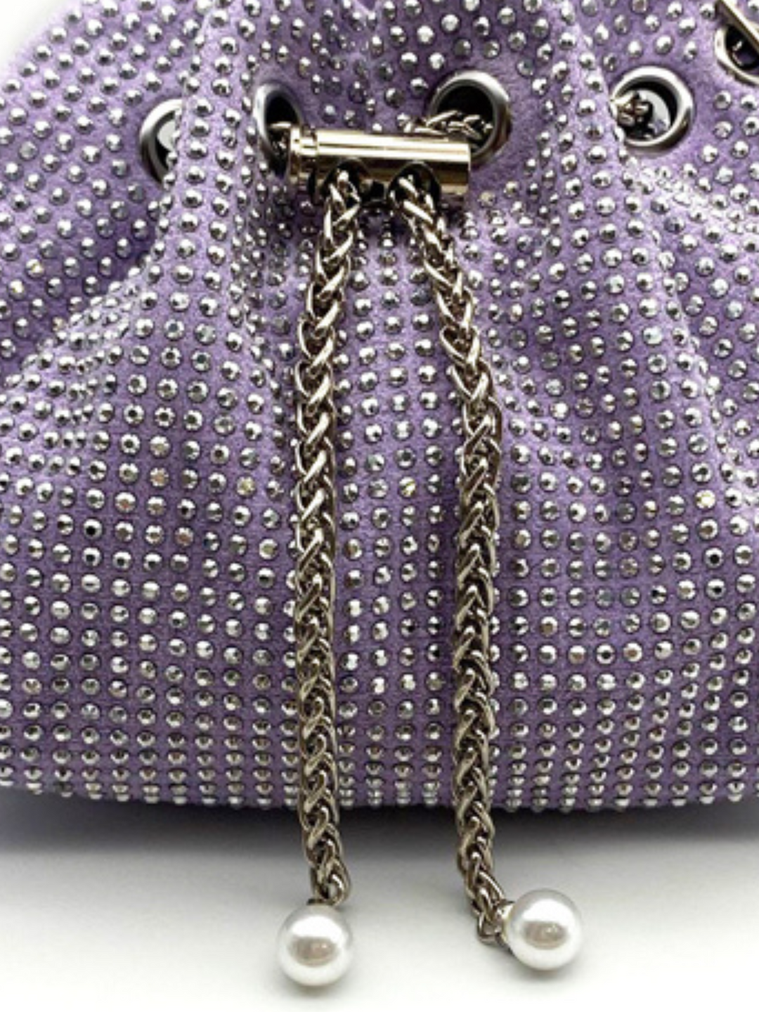 Close up of drawstring silver chain clasp, with lilac materiall and rhinestone studed design. Ther purple silver chain has pearl inserts at the end of the chain. 