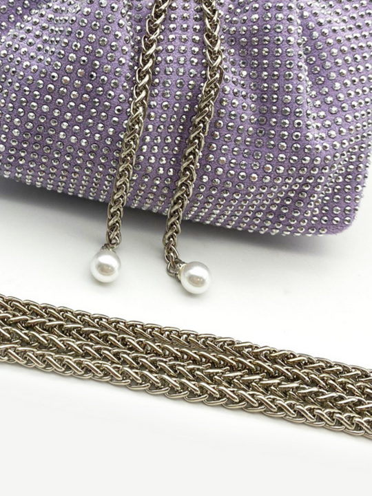 Close up of silver chain strap and purple studed bag with silver chain. The purple studed bag is placed in front of a plain background and the silver chain attachment is placed in front of the bag. 
