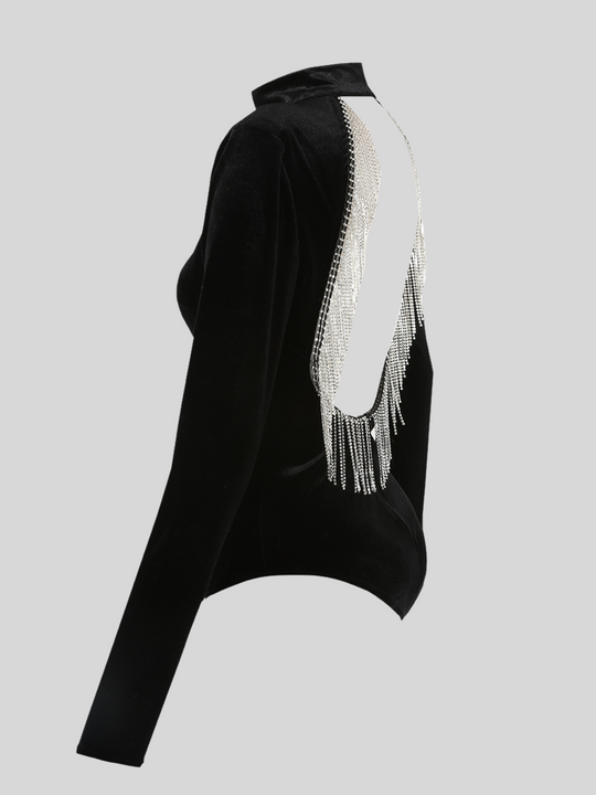 Ghost manequin wears black velvet bodysuit with an open back which has diamante tassels. The ghost manequin stands to the side, the back of the bodysuit and long sleeves can be seen.  