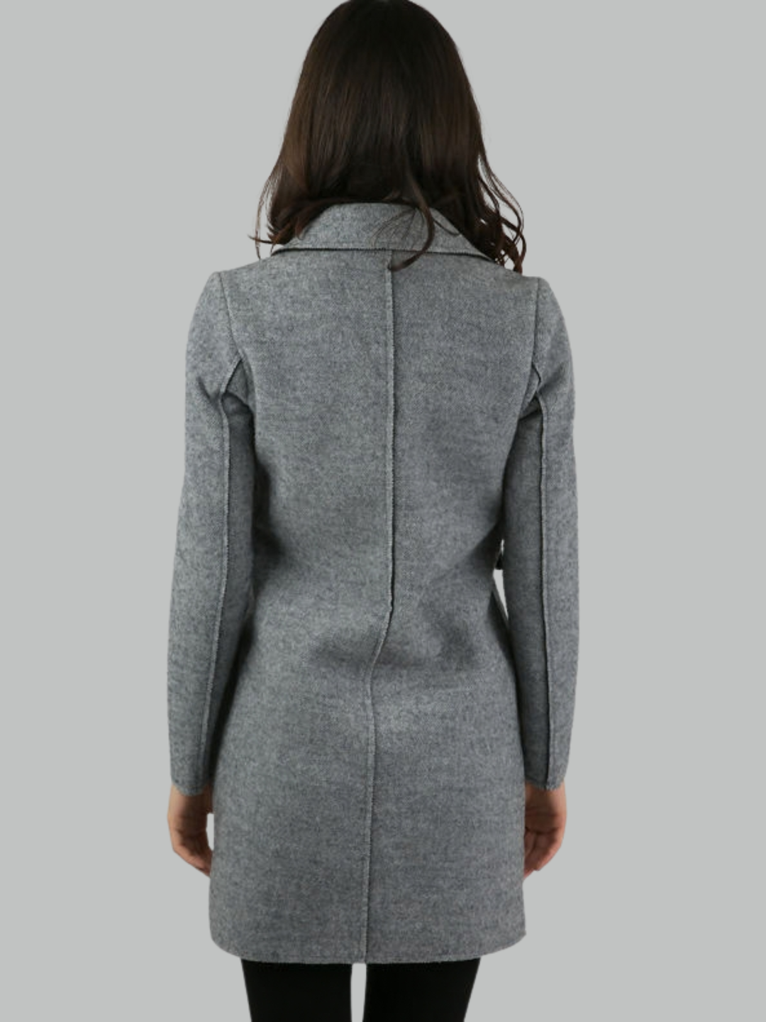 Female model stands in front of a plain background. The model wears a grey woolen coat with single front button fastening and grey tweed trim. The model has tanned skin and shoulder length hair, she stands with hher back to the camera, the back of the coat can be seen, including the exposed trim design.  